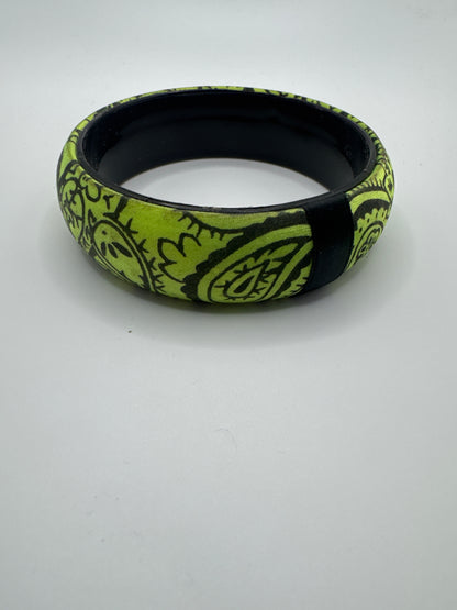 Wide lime green bangle bracelet featuring a black doodle-style line art pattern