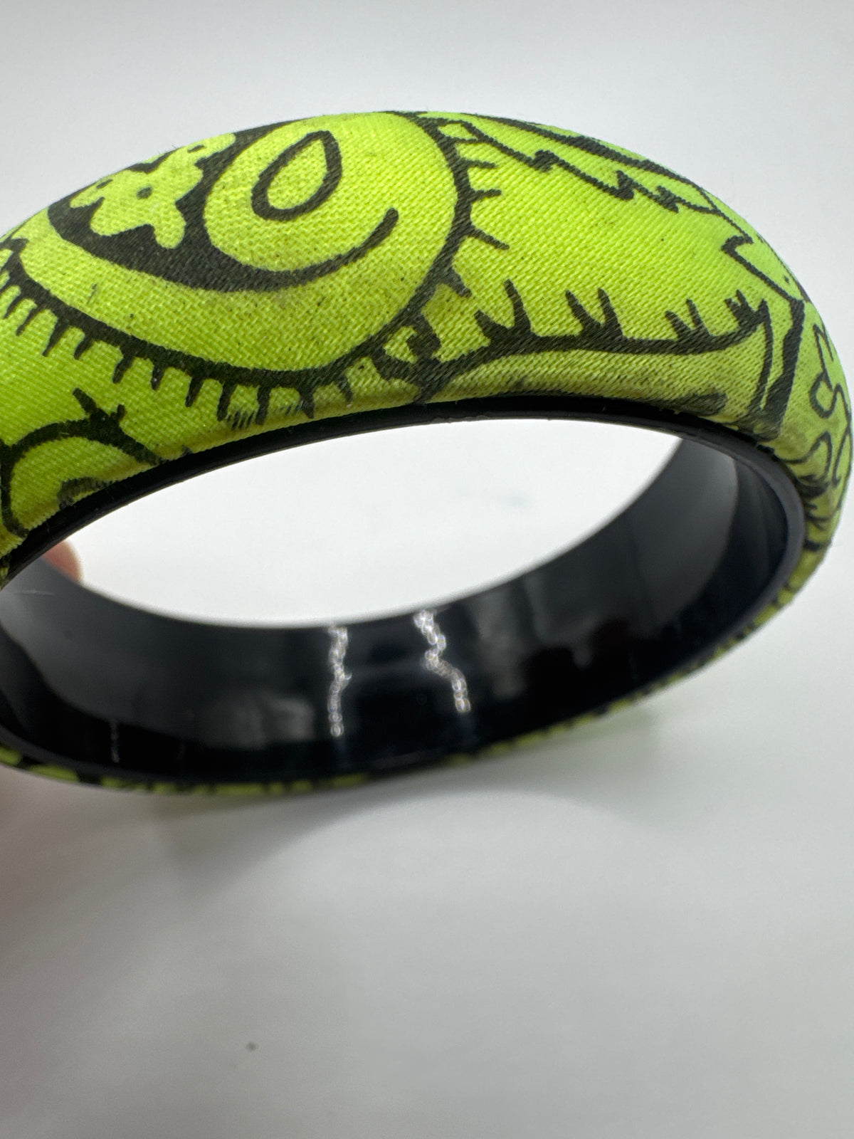 Wide lime green bangle bracelet featuring a black doodle-style line art pattern